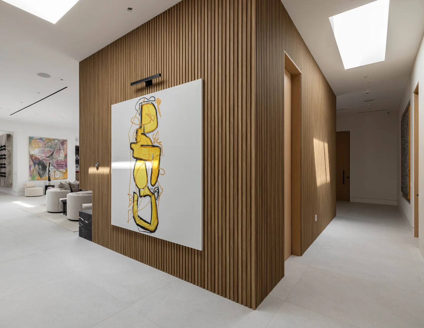 Petit Avenue gallery with vertical timber wall panels, a recessed door, stone floor and long rooflight around a corner.