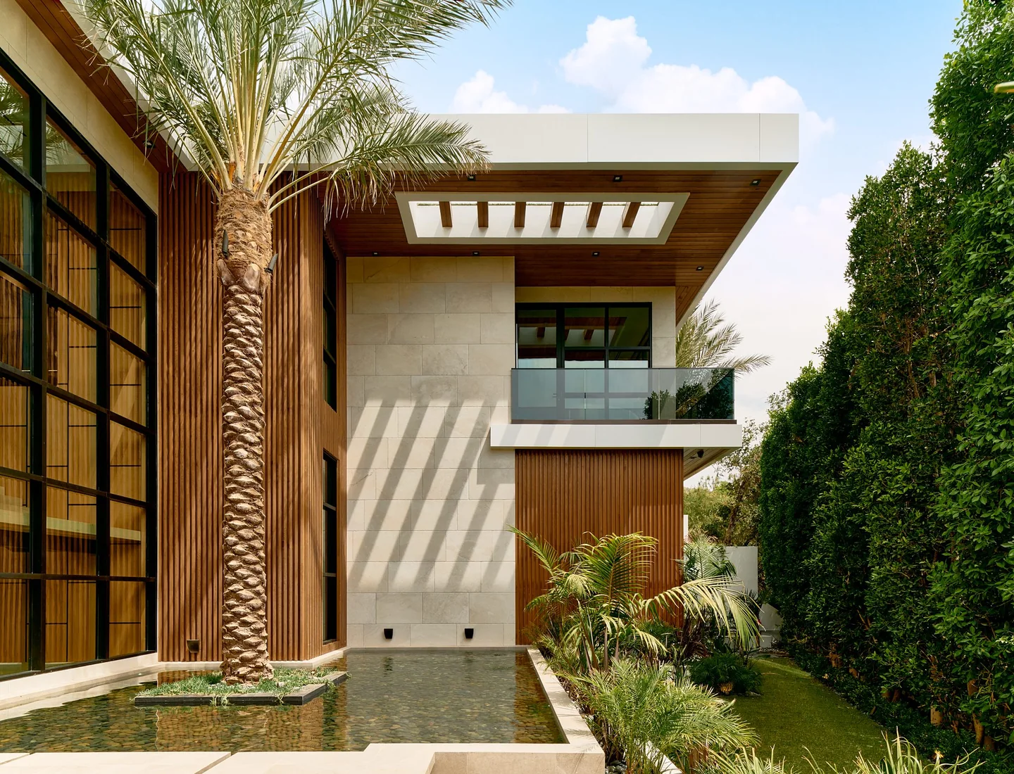 Chalon Road entrance canopy with timber soffits, tall glazing and an upper balcony beside a palm.