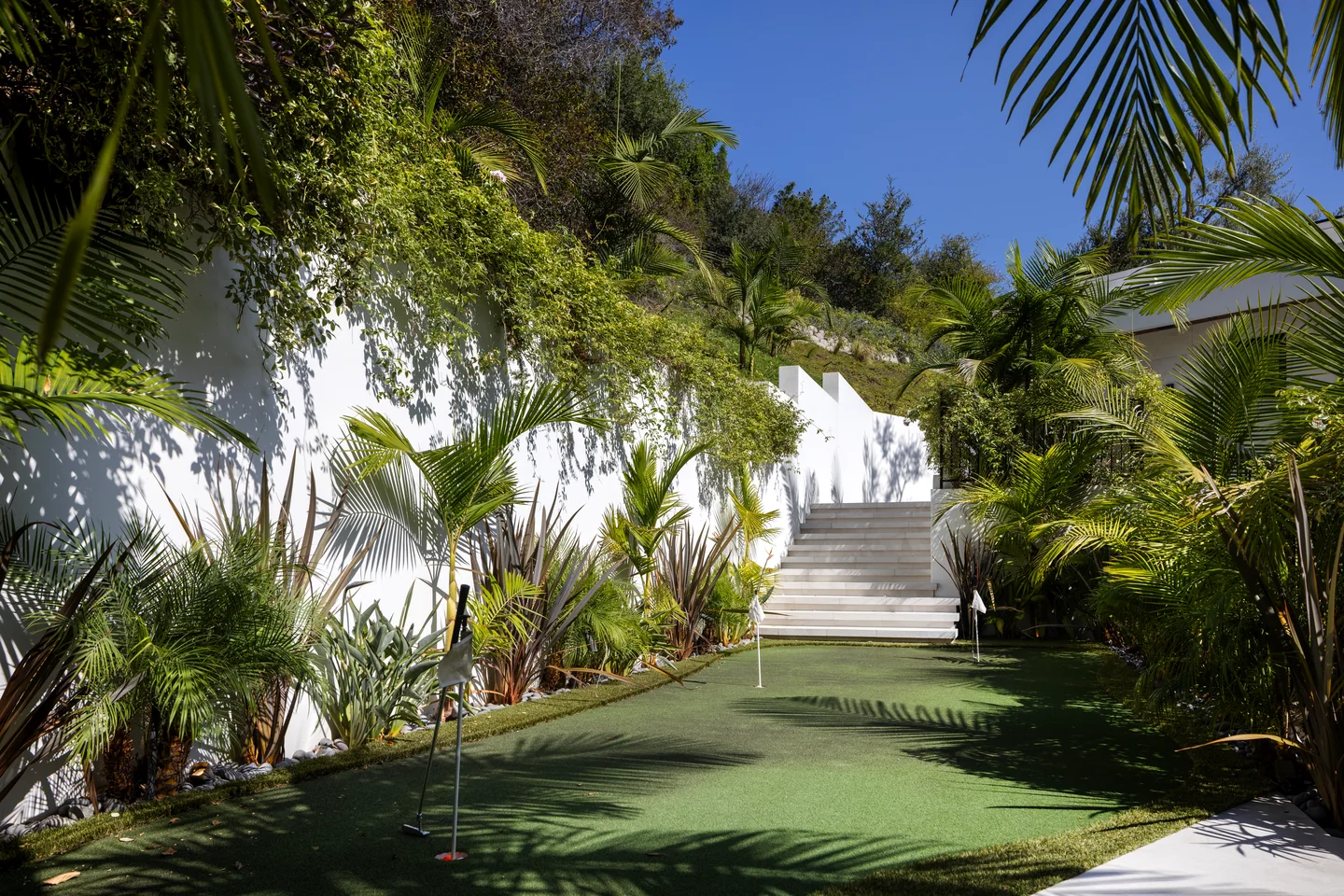 Chalon Road garden with a narrow green, palms, low planting and an outdoor stair at the far end.