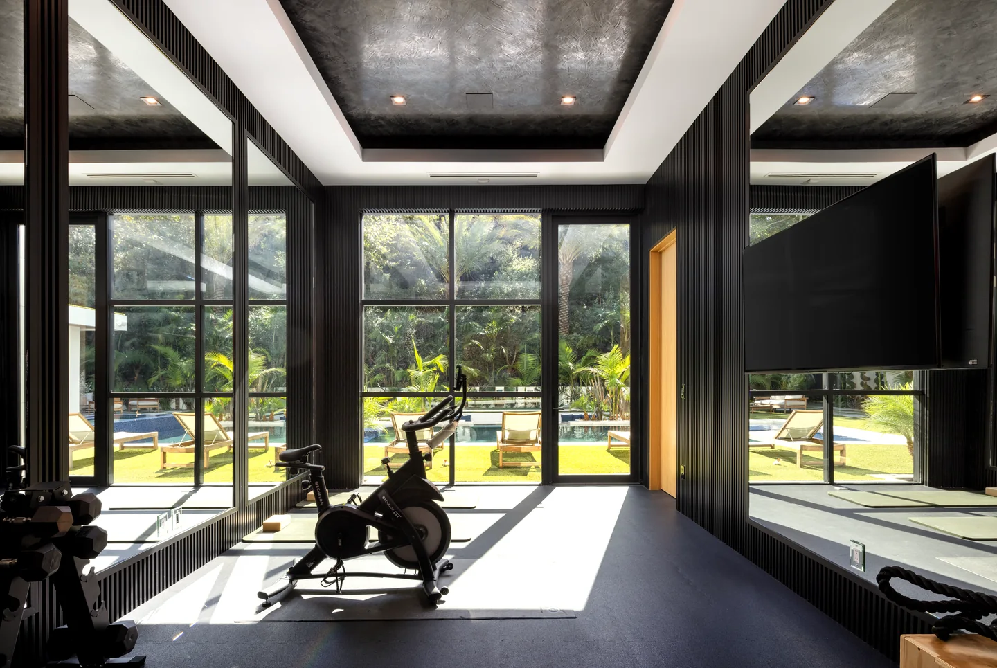 Chalon Road exercise room with a dark paneled ceiling, full-height glazing and a view to the garden.