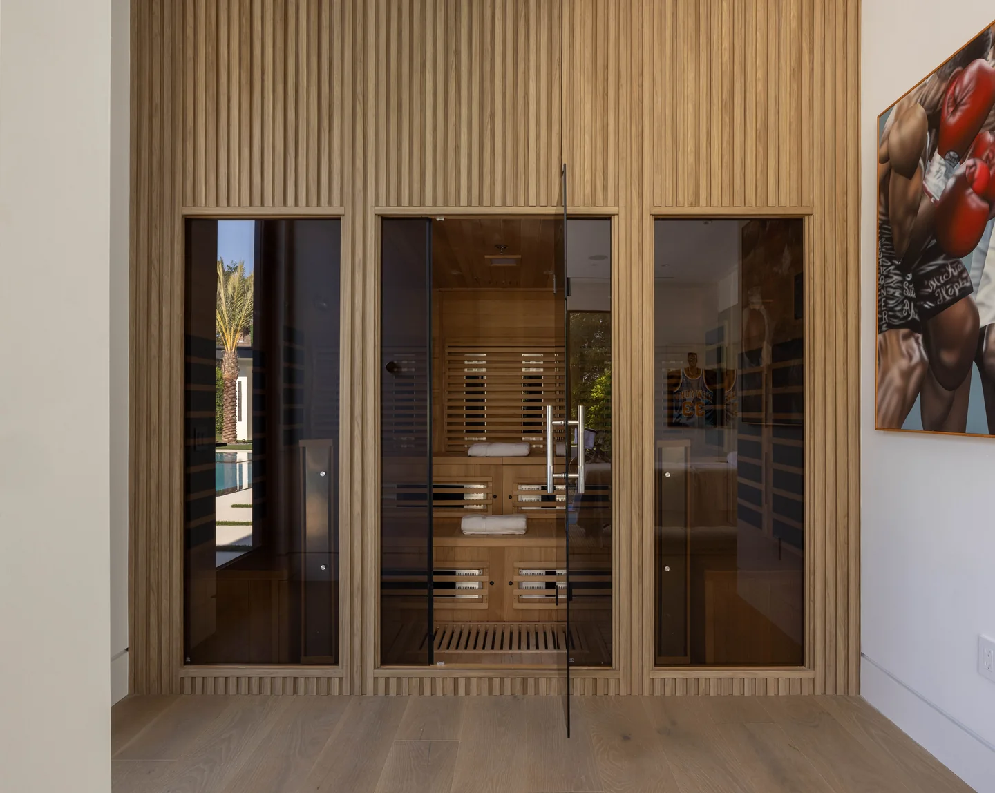 Petit Avenue sauna with glazed doors, timber-lined walls and fitted benches beside vertical wall paneling.