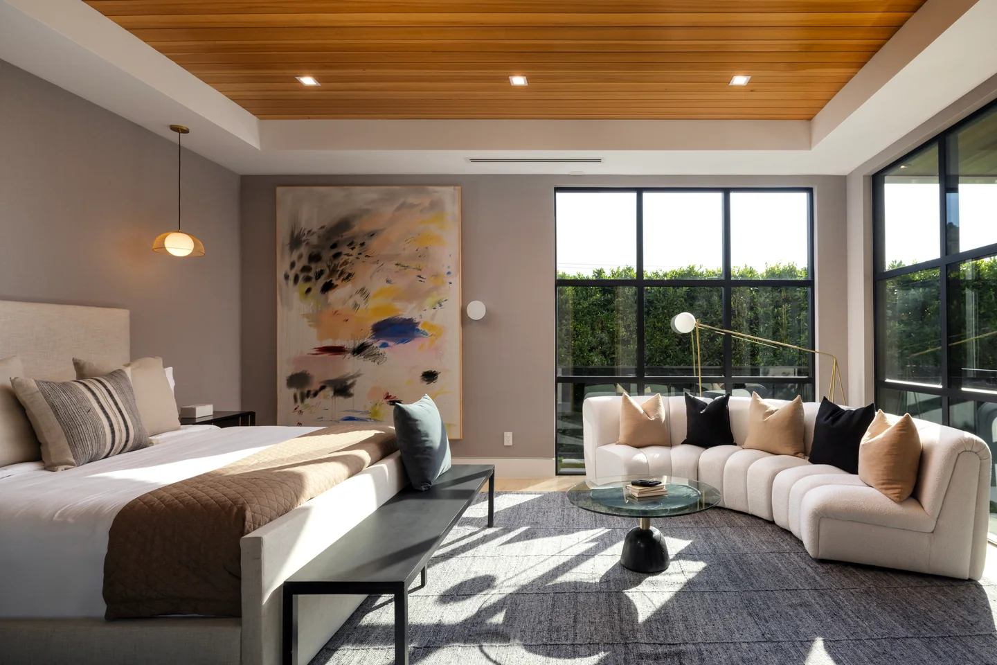 Bedroom with a timber-lined ceiling, full-height garden windows and an adjoining sitting area.