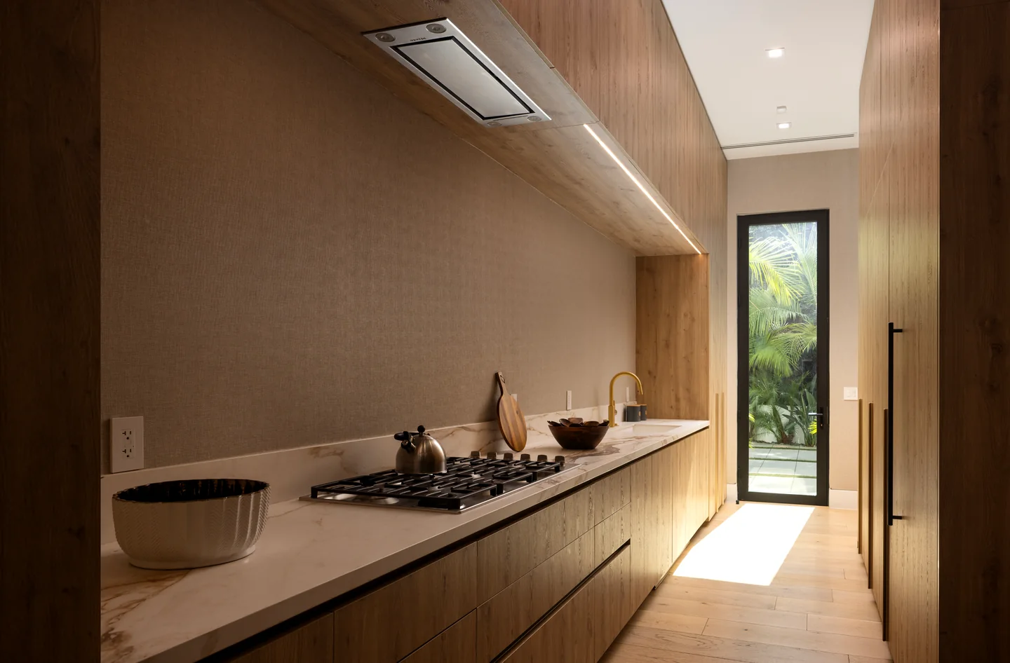 Long preparation kitchen with timber cabinetry, an inset sink and a pale continuous worktop.