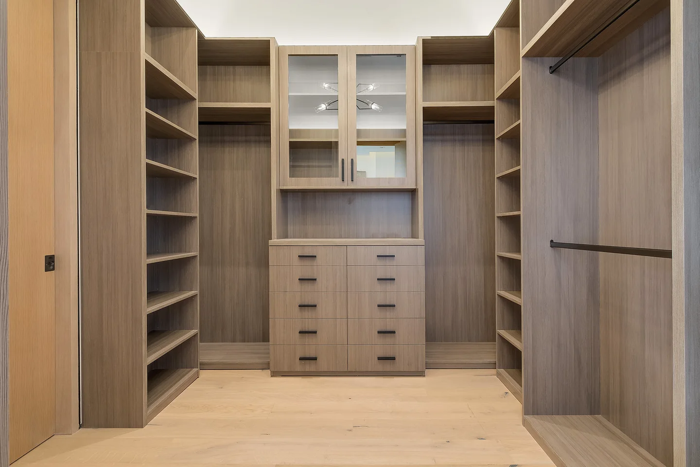 Walk-in dressing room with timber cabinetry, open shelves and a central bank of drawers.