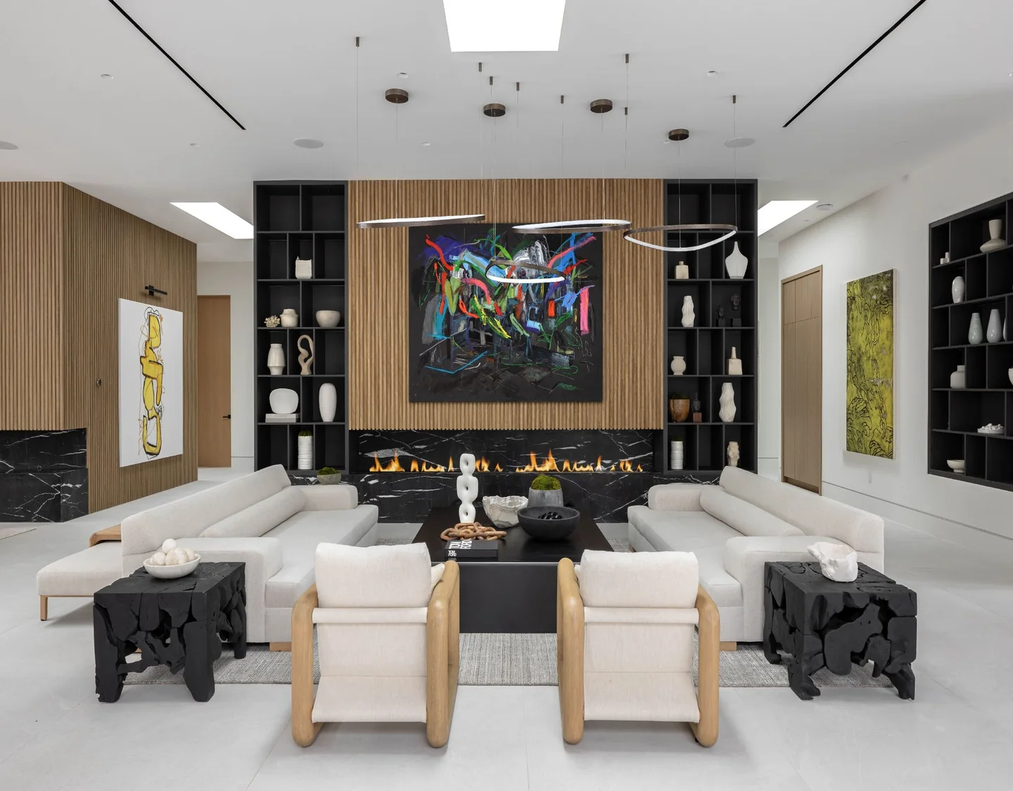 Living room with a linear fireplace, timber feature wall and bright artwork beneath a skylight.