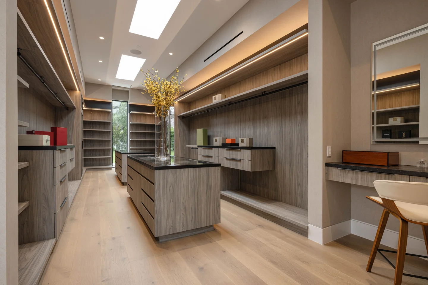 Dressing room with a central drawer island, illuminated shelving and a row of skylights.