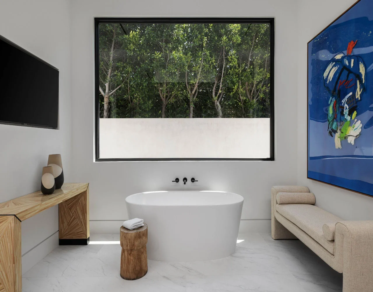 Freestanding bath beneath a broad window at Petit Avenue.