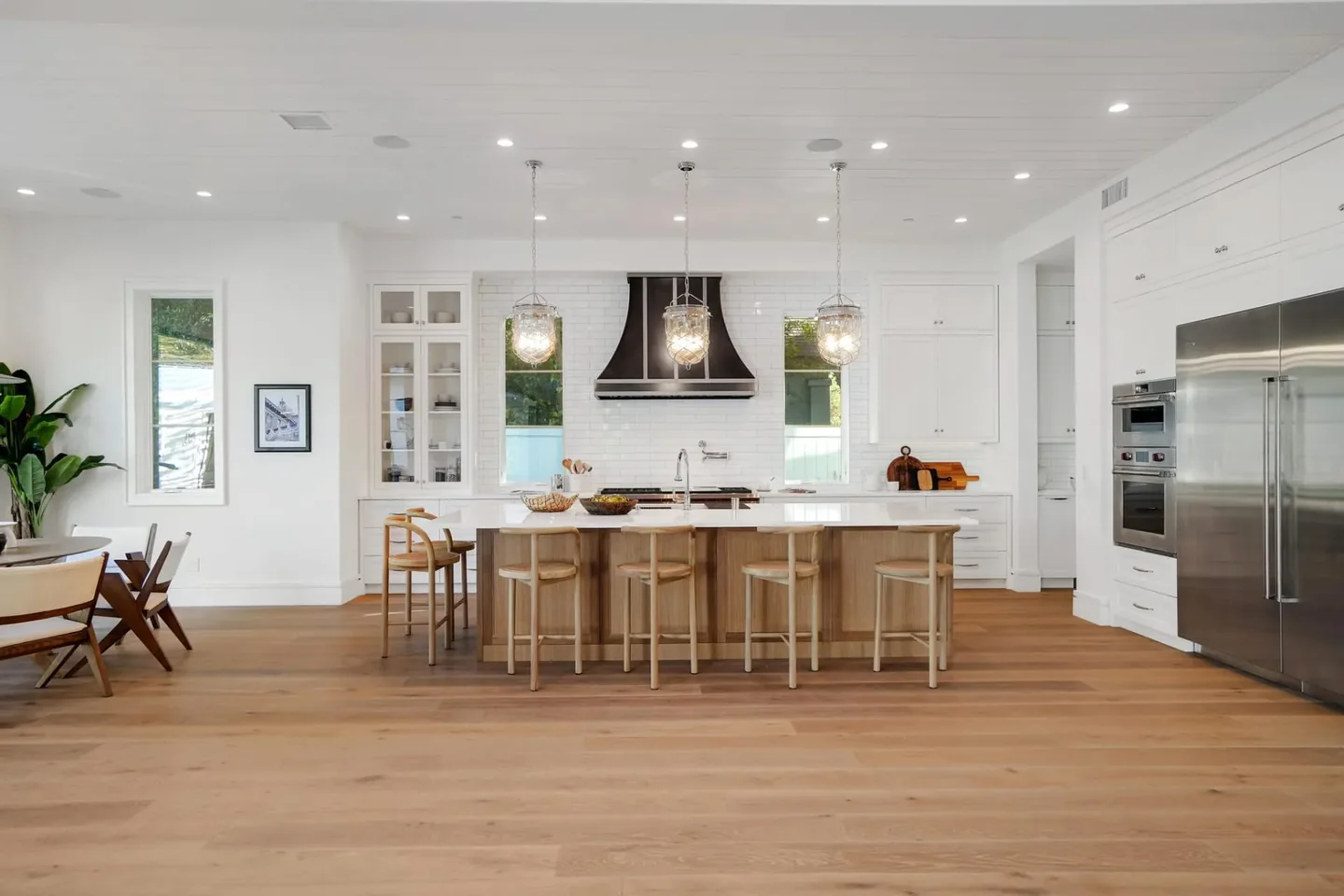 South Bundy kitchen with white fitted cabinetry, a timber island, a pale countertop and a dark range hood.