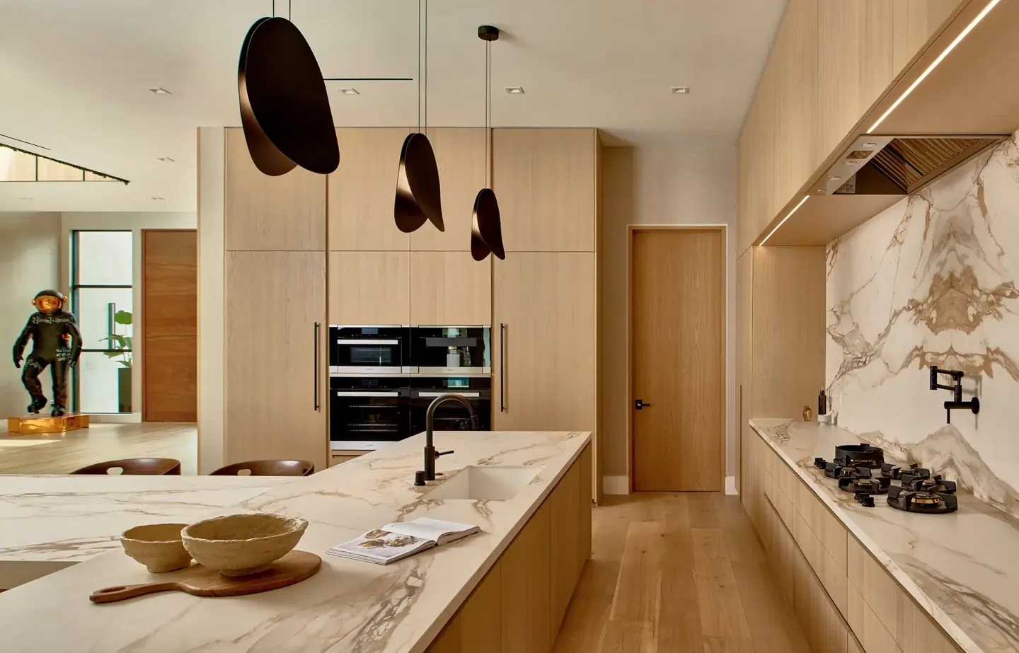 Chalon Road kitchen with timber cabinetry, a veined island and backsplash, and dark pendant lights.