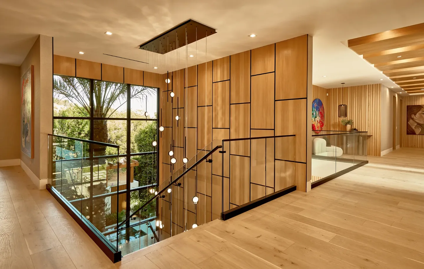 Chalon Road stair landing with timber wall panels, clear glass guarding and a slender dark handrail.