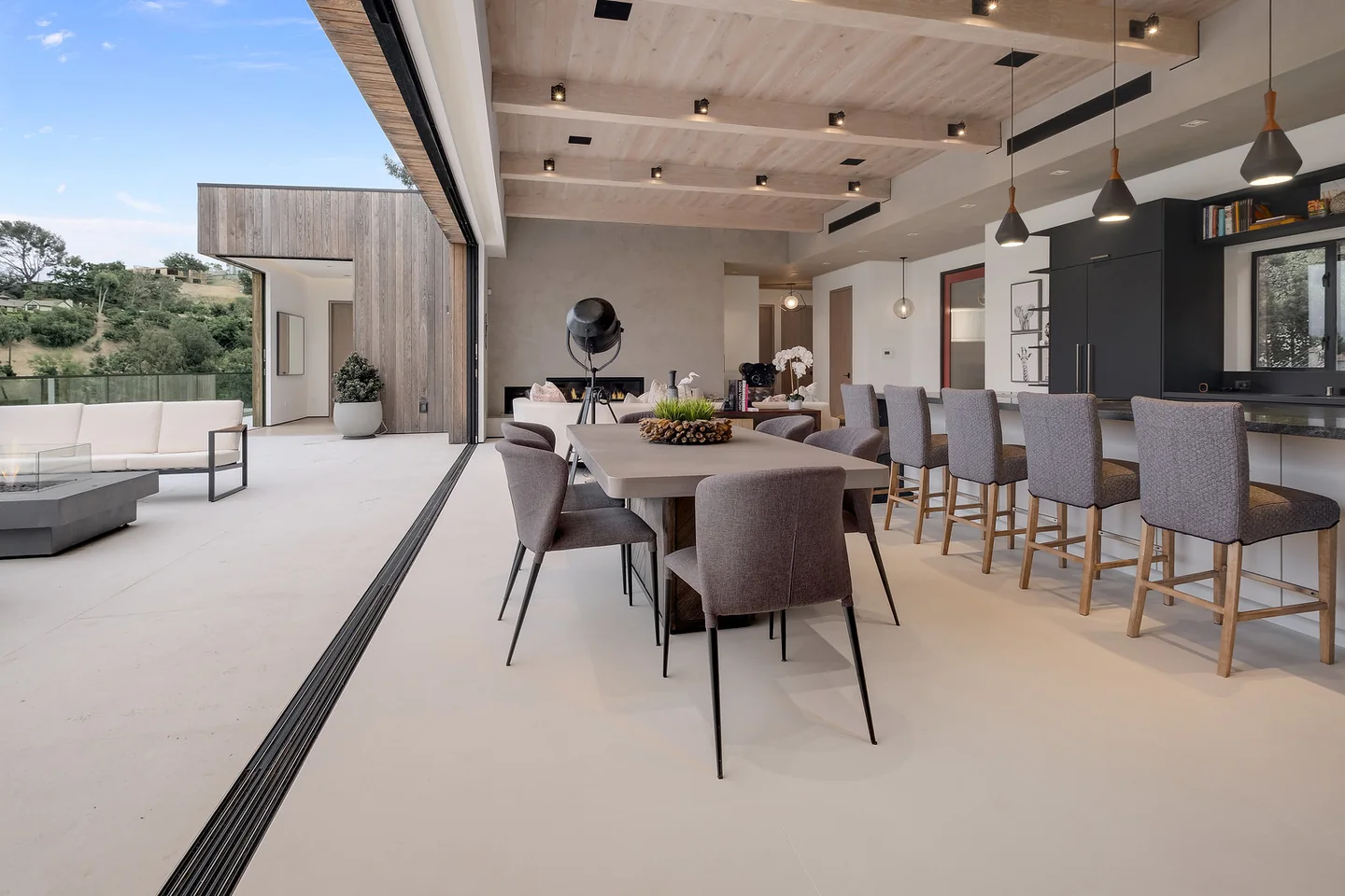 Dixie Canyon dining and kitchen space beside a fully open wall of glazing facing the terrace.