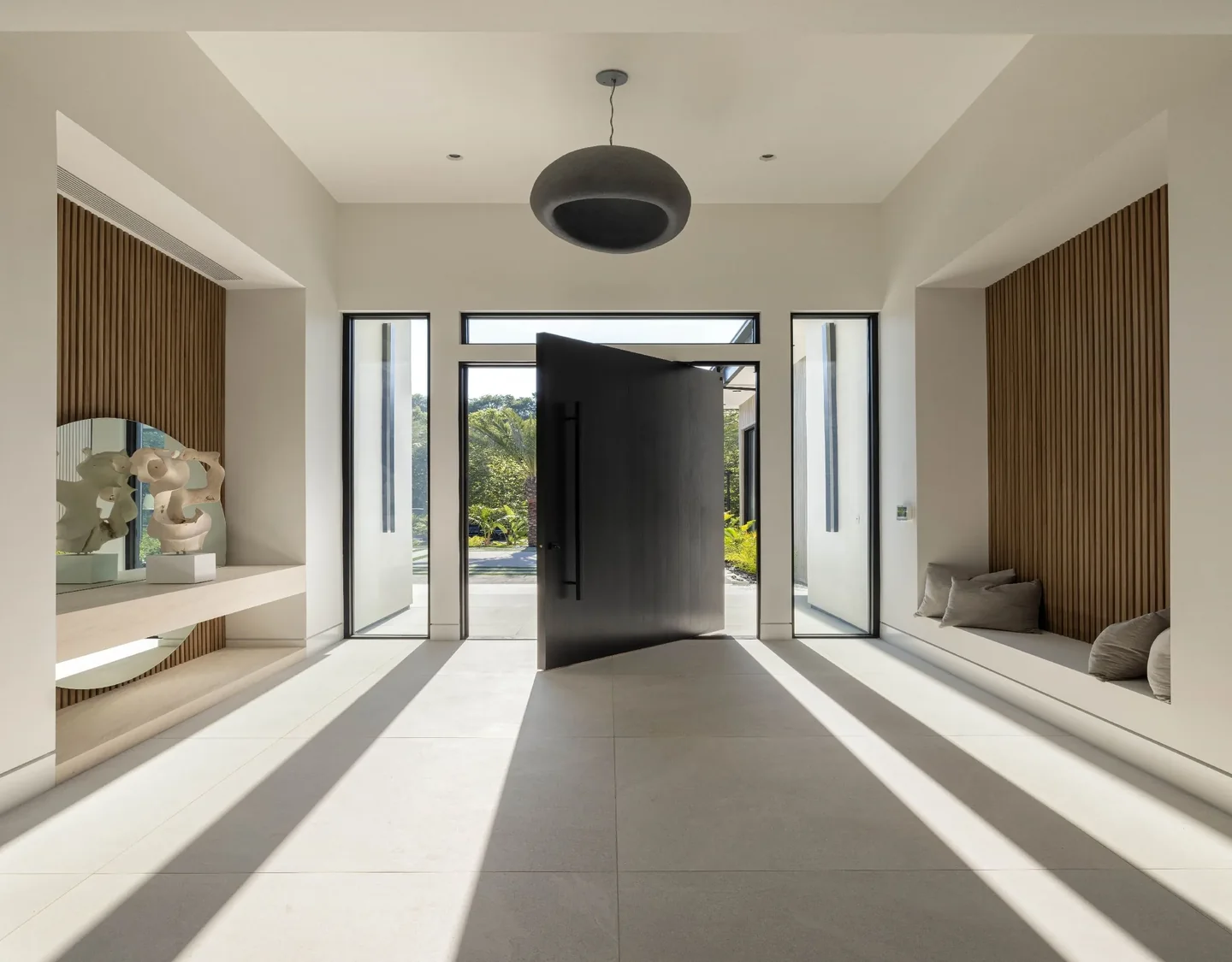 Petit Avenue entrance with a broad dark door, full-height side glazing and timber wall panels.