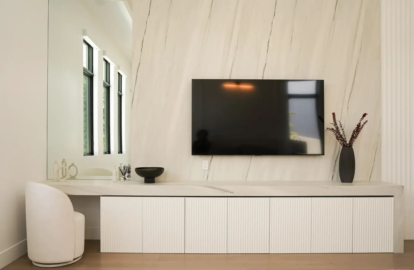 Rio Flora media wall with a pale veined surface, mounted television and low fitted cabinetry.