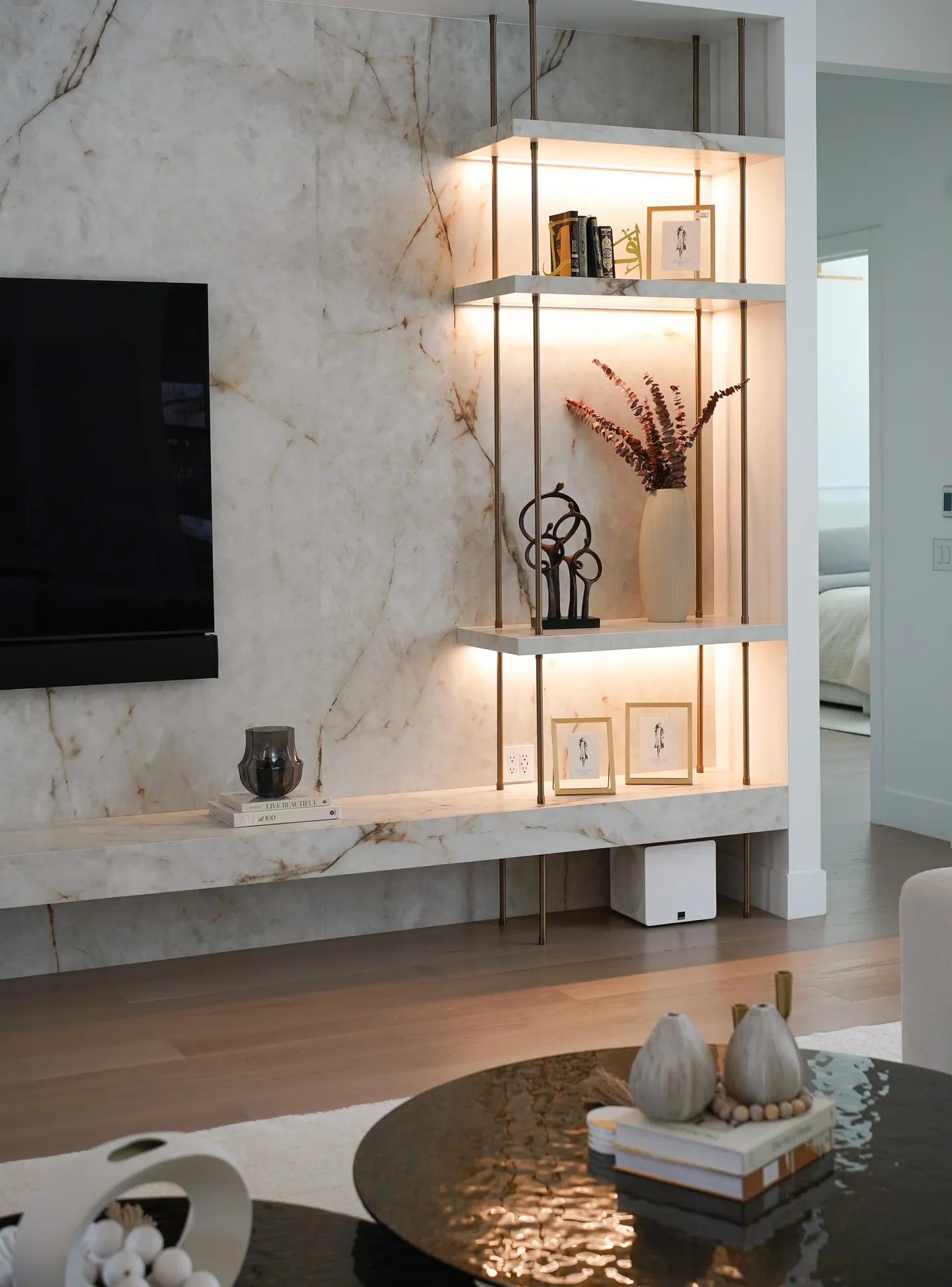 Rio Flora living room detail with a veined fireplace surround, lit open shelves and curved seating.
